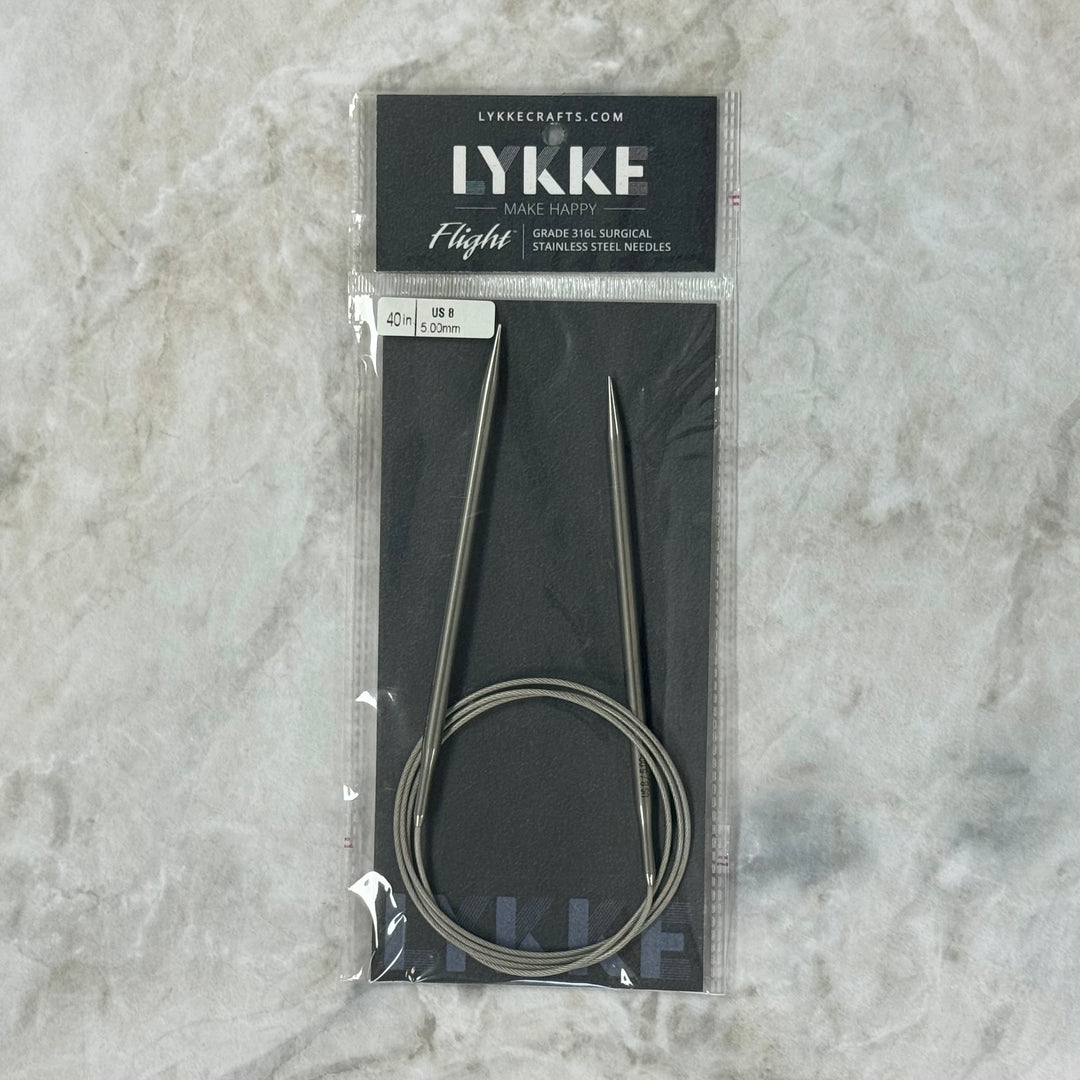 A pair of Lykke 40" Fixed Circular Surgical Stainless Steel Knitting Needles in their original black packaging, featuring the brand name &