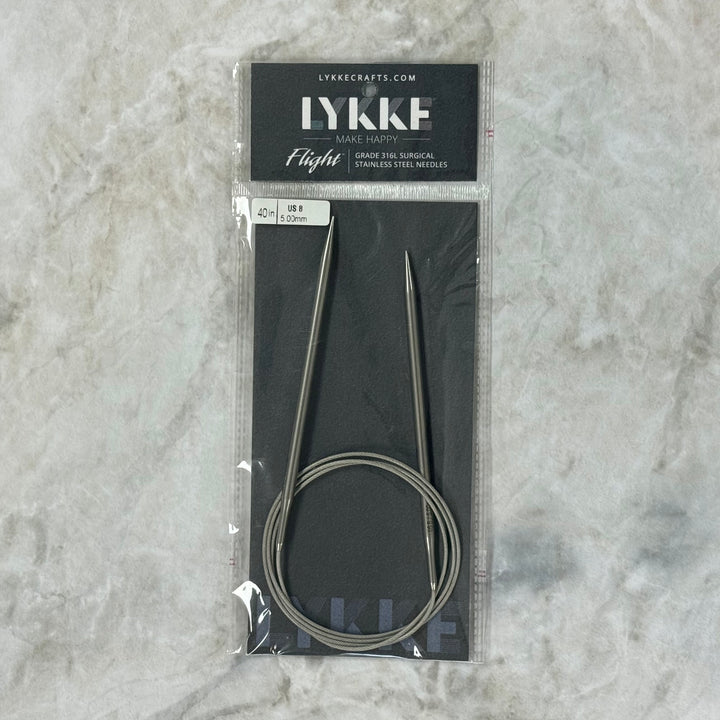 A pair of Lykke 40" Fixed Circular Surgical Stainless Steel Knitting Needles in their original black packaging, featuring the brand name &