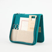 Teal punch needle kit with beige interior on a white background