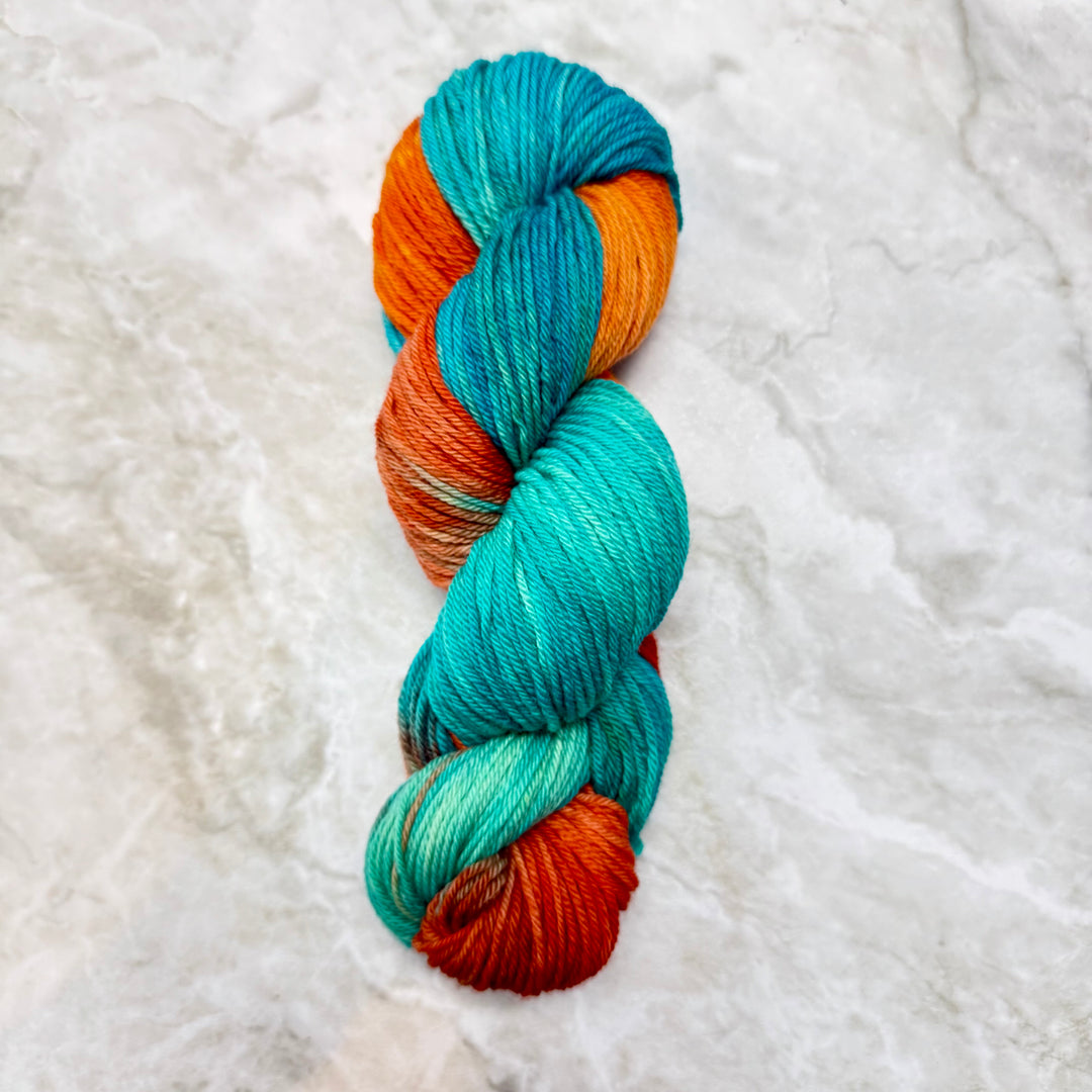 Braided skein of blue and orange yarn on a textured white background