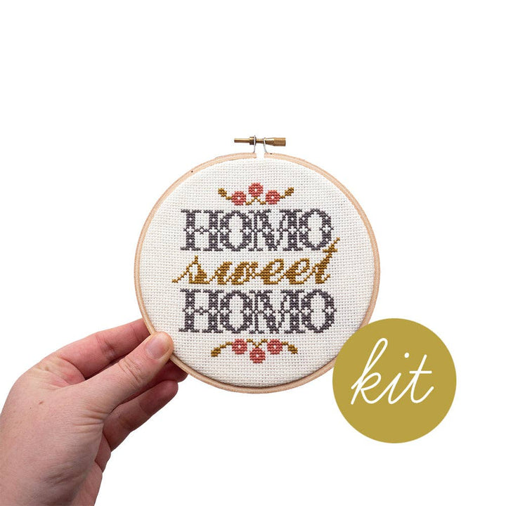 Hand holding a cross-stitched hoop with &
